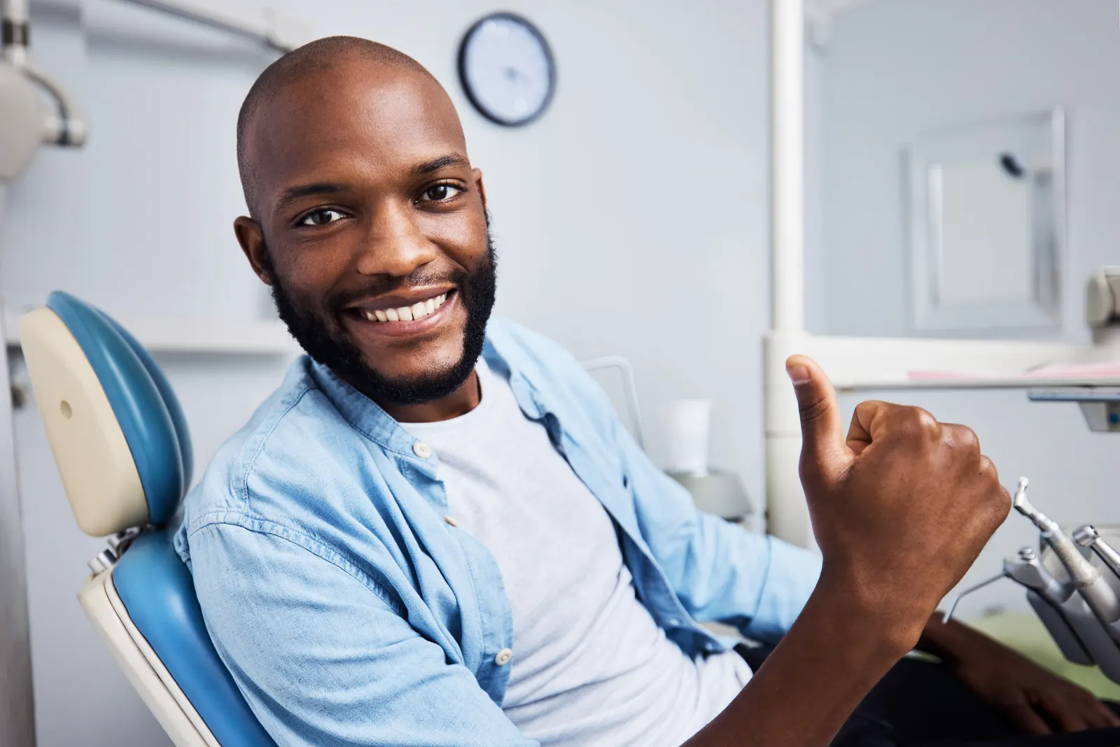 Smiling man in dental chair giving thumbs up in a dentist office.