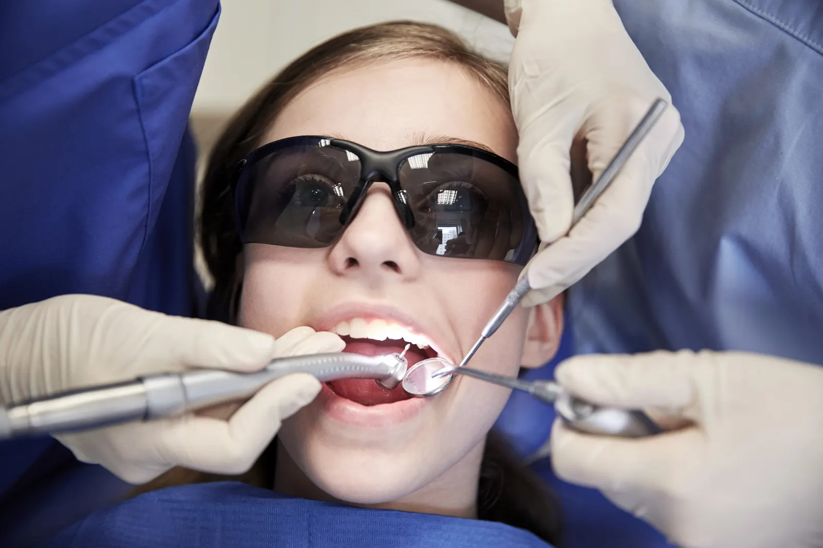 Close-up of a young patient wearing protective glasses during a dental cleaning procedure.