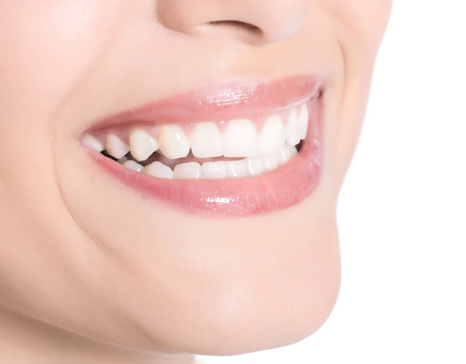 Close-up of a smiling mouth with white teeth and glossy pink lips on light skin.
